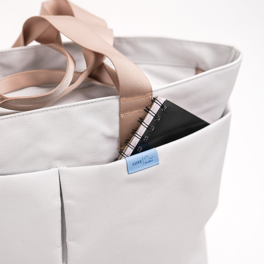 Grey totebag, a notepad is peeking out from the front pocket