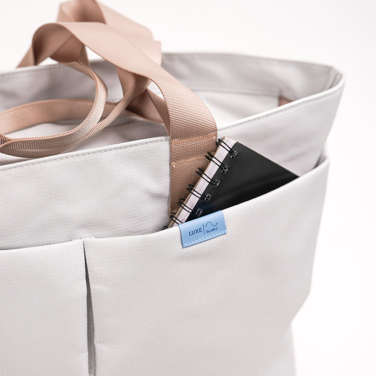 Grey Luxe totebag, a notepad is peeking out from the front pocket