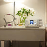CPAP machine on a nightstand with flowers and a mask