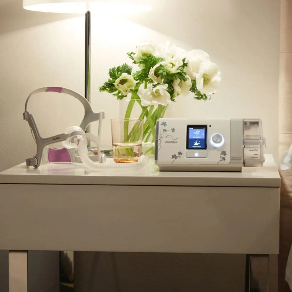 CPAP machine on a nightstand with flowers and a mask