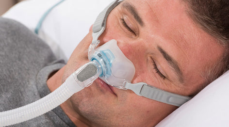 Man sleeping with CPAP therapy using Fisher and Paykel Brevida Nasal Pillow Mask